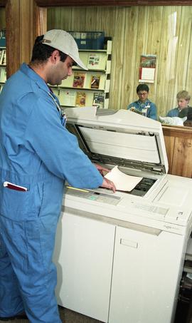 Student in coveralls using a photocopier [4 of 5 photographs]