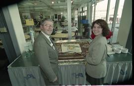 Open House 1998; man and woman hold knives over Open House chocolate cake [photograph 3 of 4]
