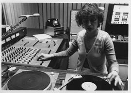 Broadcast Communication, 1980s; woman using turntables and control panel in the radio booth [2 of 2]