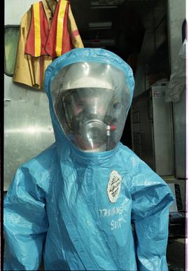 Open House 1998; person standing in training suit made of tarp with gas mask underneath [photogra...