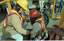 Open House 1998; woman in safety gear and line is lowered into confined space with assistance by ...
