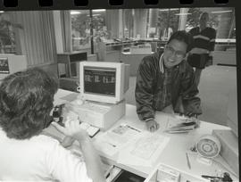 Communications Relations Opening Day 1991;  man smiling to registrar worker sitting in front of c...