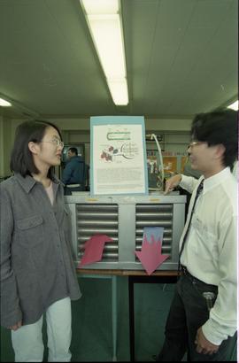 Open House 1998; student in business attire explains heat pipe to woman [photograph 2 of 2]
