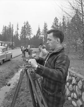 Survey, 1964; a man using a surveying level and another man holding a measuring tape [1 of 2]