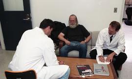 Three men sitting around a coffee table with human gait textbooks between them