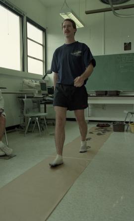 Man walking on paper creating ink footprints [7 of 9 photographs]